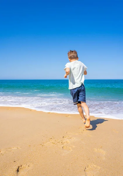 Boldog fiú fut és játszik a nyári strandon. Fiatal tinédzser pihenni és szórakozni nyári nyaralás utazás. — Stock Fotó
