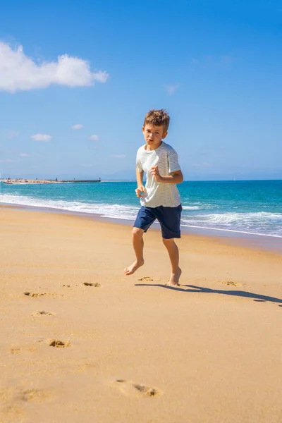 Szczęśliwy chłopak biegający i bawiący się na letniej plaży. Młody nastolatek zrelaksować się i zabawy w letnie wakacje podróży. — Zdjęcie stockowe