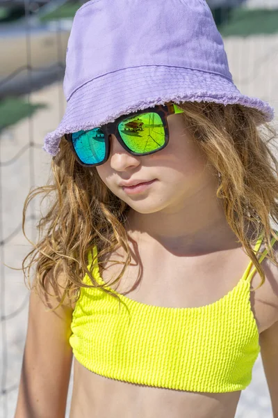 帽子とサングラスをビーチにポーズをとって若い美しいモデルの女の子の肖像画。明るい黄色のビキニ水着を着て。夏の日白い砂. — ストック写真