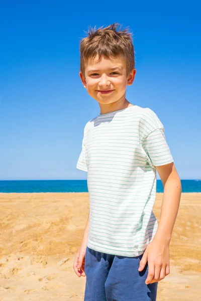 Szczęśliwy chłopak stoi na letniej plaży. Młody nastolatek zrelaksować się i zabawy w letnie wakacje podróży. — Zdjęcie stockowe