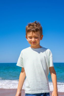 Yaz plajında duran mutlu çocuk. Genç delikanlı yaz tatili seyahatinde rahatlıyor ve eğleniyor..