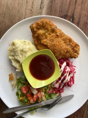 bir tabak tavuk şnitzel. Ekmeğin yanında kremalı patates püresi ve taze lahana salatası ve taze bahçe salatasıyla mükemmel bir altın-kahverengi çıtır çıtır var..
