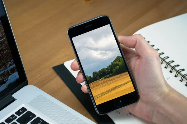 IPhone 6 hold in hand top of wood table — Stock Photo, Image