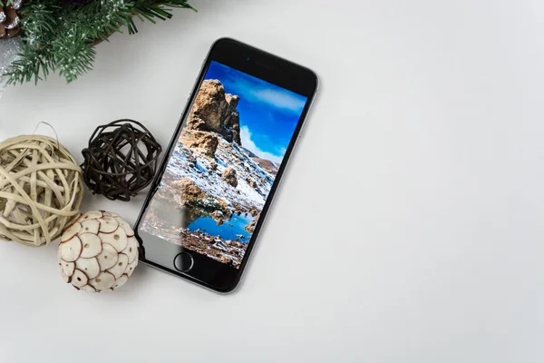 IPhone 6 του παρόντος για τα Χριστούγεννα με τα Χριστούγεννα στολίδια σε άσπρο φόντο — Φωτογραφία Αρχείου