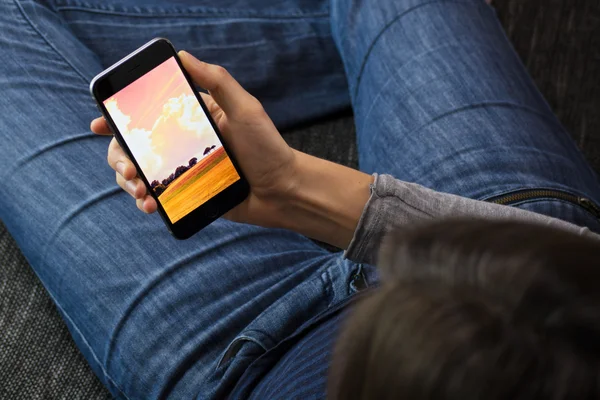 Mulher segurando um iPhone 6 no sofá — Fotografia de Stock