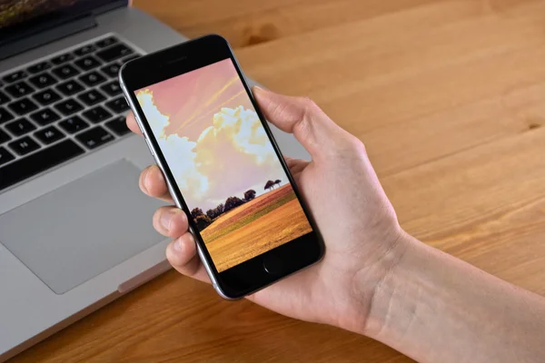 IPhone 6 hold in hand with a Macbook — Zdjęcie stockowe