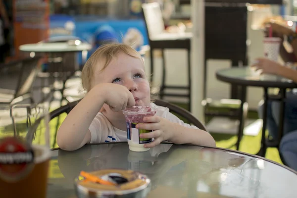 Niño soñador come yogur en la mesa —  Fotos de Stock