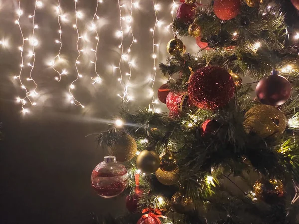 Kerst versierde boom in het donker en bloemenslinger op de muur — Stockfoto