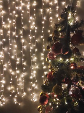 Karanlıkta Noel süslenmiş ağaç ve duvarda çelenk