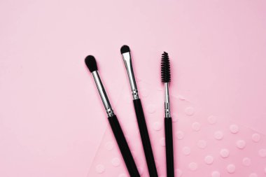 Pembe arka planda makyaj için kozmetik fırçalar, moda ve güzellik