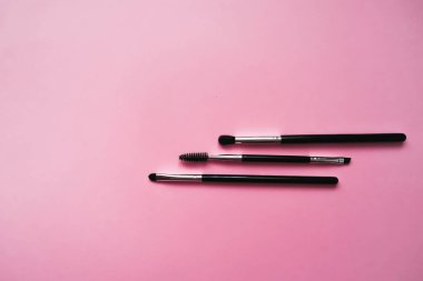 Pembe arka planda makyaj için kozmetik fırçalar, moda ve güzellik