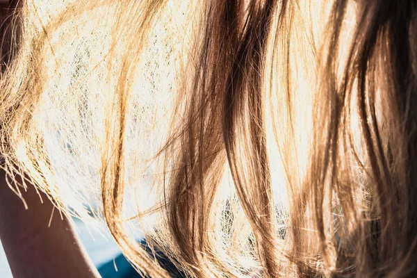 Güneş saçlarının arasından parlıyor.