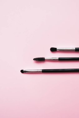 Pembe arka planda makyaj için kozmetik fırçalar, moda ve güzellik