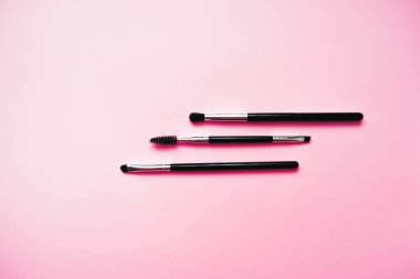 Pembe arka planda makyaj için kozmetik fırçalar, moda ve güzellik