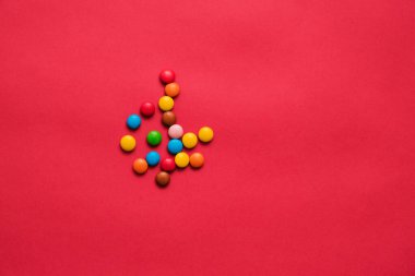 Kırmızı zemin üzerinde çeşitli renkte tatlılar sürükleniyor