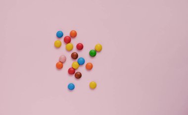 Pembe arka planda çeşitli renkte tatlılar.