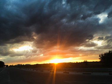 Parlak günbatımı yol üzerinde, kara bulutlar