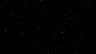 Beyaz toz parçacıklarının büyüleyici bir görüntüsü derin siyah bir arkaplan üzerinde zarafetle yüzüyor, ruhani ve soyut bir görsel yaratıyor..