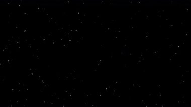 Küçük beyaz parçacıkların büyüleyici bir görüntüsü yavaşça sürükleniyor ve siyah bir arka plana doğru parıldıyor, dingin ve ruhani bir görsel etki yaratıyor..