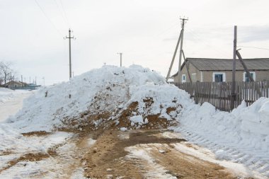 Köydeki yol kardan temizlendi ve güvenli trafik için kumla kaplandı. Kar yol boyunca sürükleniyor. Kışın güvenli yol trafiği kavramı
