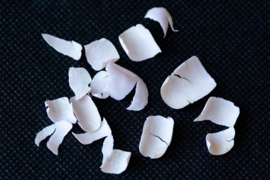 Tırnaklardan çıkarılan jel cilasının yakın çekimi, siyah arka planda kırılmış sahte akrilik tırnak parçaları..