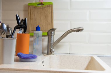 Boş lavabo. Bulaşıkları önden yıkama hazırlığı. Temiz çatallar, bıçaklar ve kaşıklar bir konteynırda duruyor. Ev ödevi.