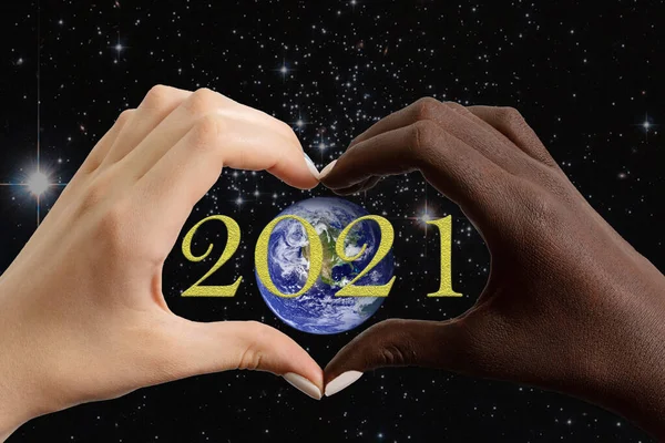 Yeni yıl 2021 tebrik kartı. Yıldızlı gökyüzünün arka planına ve 2021 rakamlarına karşı Dünya gezegeni şeklinde siyah ve beyaz eller. Bu görüntünün elementleri NASA tarafından desteklenmektedir