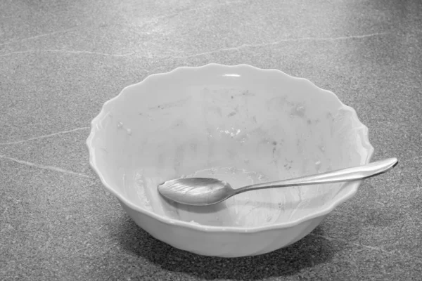 Пустая грязная белая тарелка с крошками от десерта и ложкой на сером бетонном фоне, вид спереди — стоковое фото