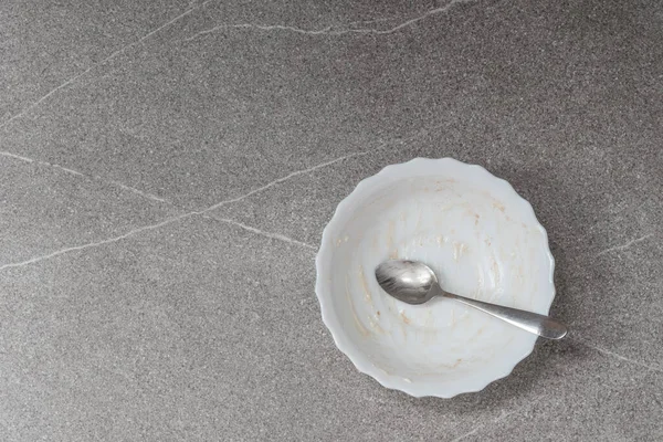 Boş beyaz tabak, kırıntılar ve gri kaşık 2021 son trend arka plan, üst görünüm