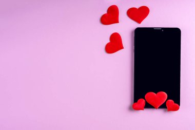 Pembe zemin üzerinde kırmızı kalp şekli olan siyah boş telefon ekranı, kopyalama alanı, minimalizm, düz uzanma