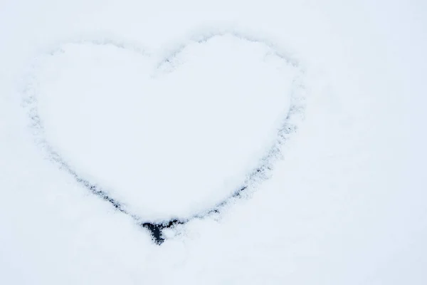 Un symbole en forme de cœur est dessiné sur la texture de la neige blanche. La manifestation de l'amour sous la forme d'une image du cœur. Concept Saint-Valentin — Photo