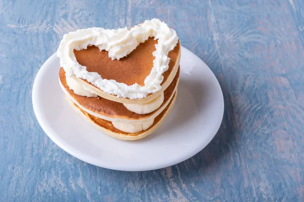 Valentines day creative breakfast. Homemade heart shaped pancake with banana decorated with white cream — Stock Photo, Image