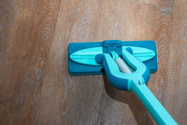 House cleaning concept. Washing the floor with a blue mop, wet laminate or parquet, close-up, top view —  Fotos de Stock