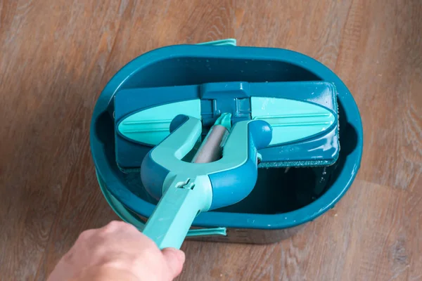 House cleaning concept. Female hand holding a blue mop over a bucket of water, close-up, top view —  Fotos de Stock