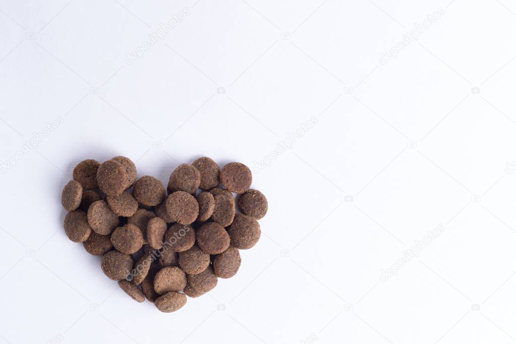 Dry pet food for dogs and cats in the shape of a heart isolated on white background, copy space, top view