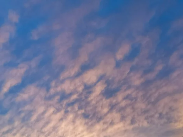 Nubes blancas y rosadas en el cielo azul. El sol ilumina las nubes con luz rosa. Fondo hermoso cielo natural — Foto de Stock