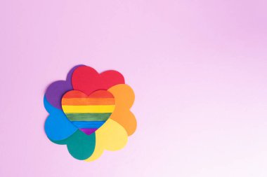 Çok renkli kağıt kalpler, gökkuşağı yapraklarıyla bir çiçek şekli oluşturur ve merkezinde pembe bir arkaplan, kopyalama alanı. LGBT kavramı