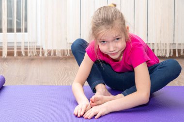 Beyaz tenli küçük kız evde fitness egzersizi yapıyor. Esneme egzersizleri. Çocuk fitness konsepti