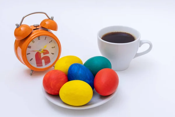 Easter breakfast concept. Hand-painted Easter eggs, mug with coffee or hot chocolate, alarm clock