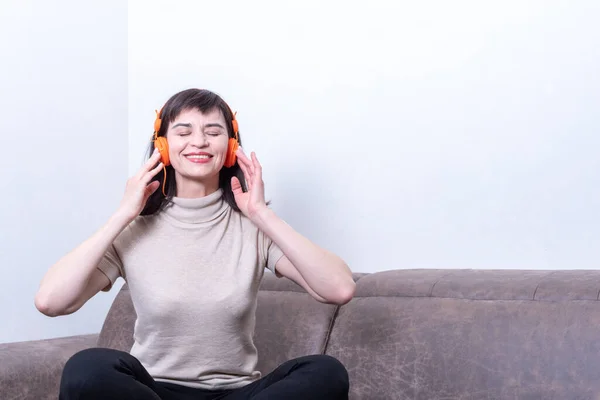 Concepto de estilo de vida - retrato de una hermosa mujer sonriente relajándose escuchando música en el teléfono móvil en casa — Foto de Stock