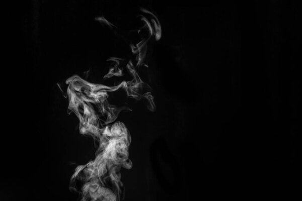 Perfect mystical curly white steam or smoke isolated on black background. Abstract background fog or smog, design element for Halloween, layout for collages.
