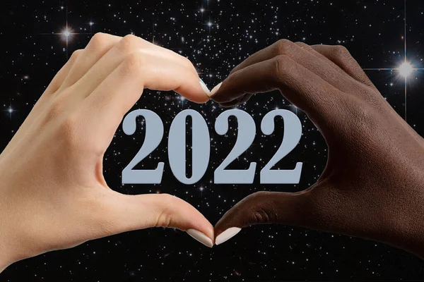Cartão de Ano Novo 2022. Mãos pretas e brancas na forma de um coração em um fundo do céu estrelado e 2022 — Fotografia de Stock