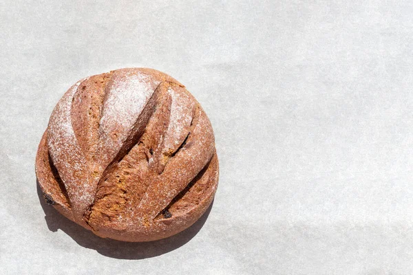 Pane di segale fatto in casa appena sfornato rotondo all'uva passa su carta da forno, vista dall'alto, spazio per la copia. Concetto di cibo sano — Foto Stock