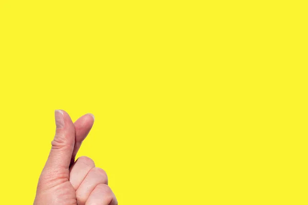A hand making a heart shape with two fingers on a bright yellow background. Korean symbol of love with fingers — Stock Photo, Image