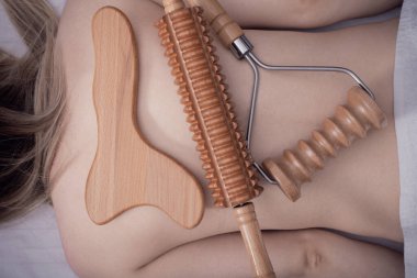 Madero terapisi, anti-selülit rahatlatıcı masaj - ahşap masaj aletleri patinaj, merdane, plaka bir kadının sırtında yatıyor, üst manzara, yakın çekim.