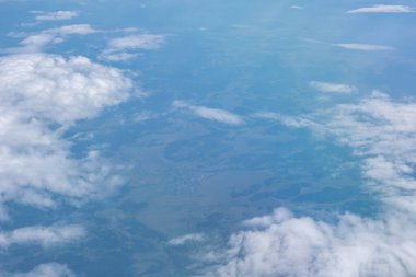 Uçaktan güzel kümülüse mavi gökyüzündeki beyaz bulutlar yeşil tarlalar, şehirler, yeryüzünün yüzeyi..