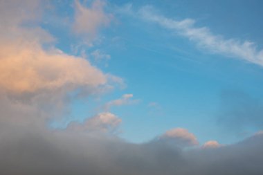 Viski gibi beyaz bulutlar ve mavi gökyüzü dalış çerçevesi fotokopi uzayı ile çapraz. Gökyüzündeki mavi-gri bulutlar batan güneşle aydınlanıyor..