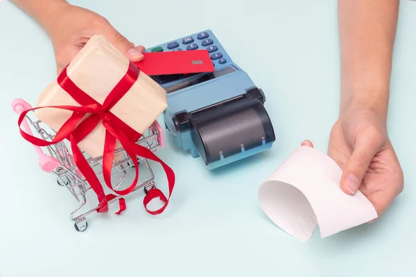 Payment by credit card, bank card at the cash register for the purchase of a gift, the hand giving the cashiers check. — Stock Photo, Image