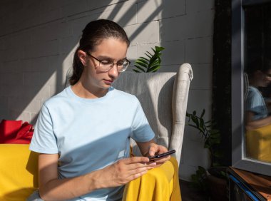 Cep telefonu kullanan güzel kız öğrenci, SMS, mesaj, internet araması, kafe uygulamaları, sert ışık