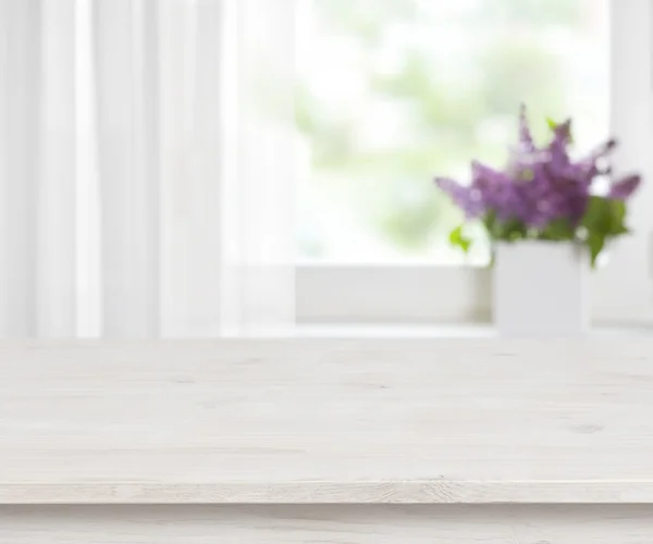 Wooden table on defocused window with purple flower pot background